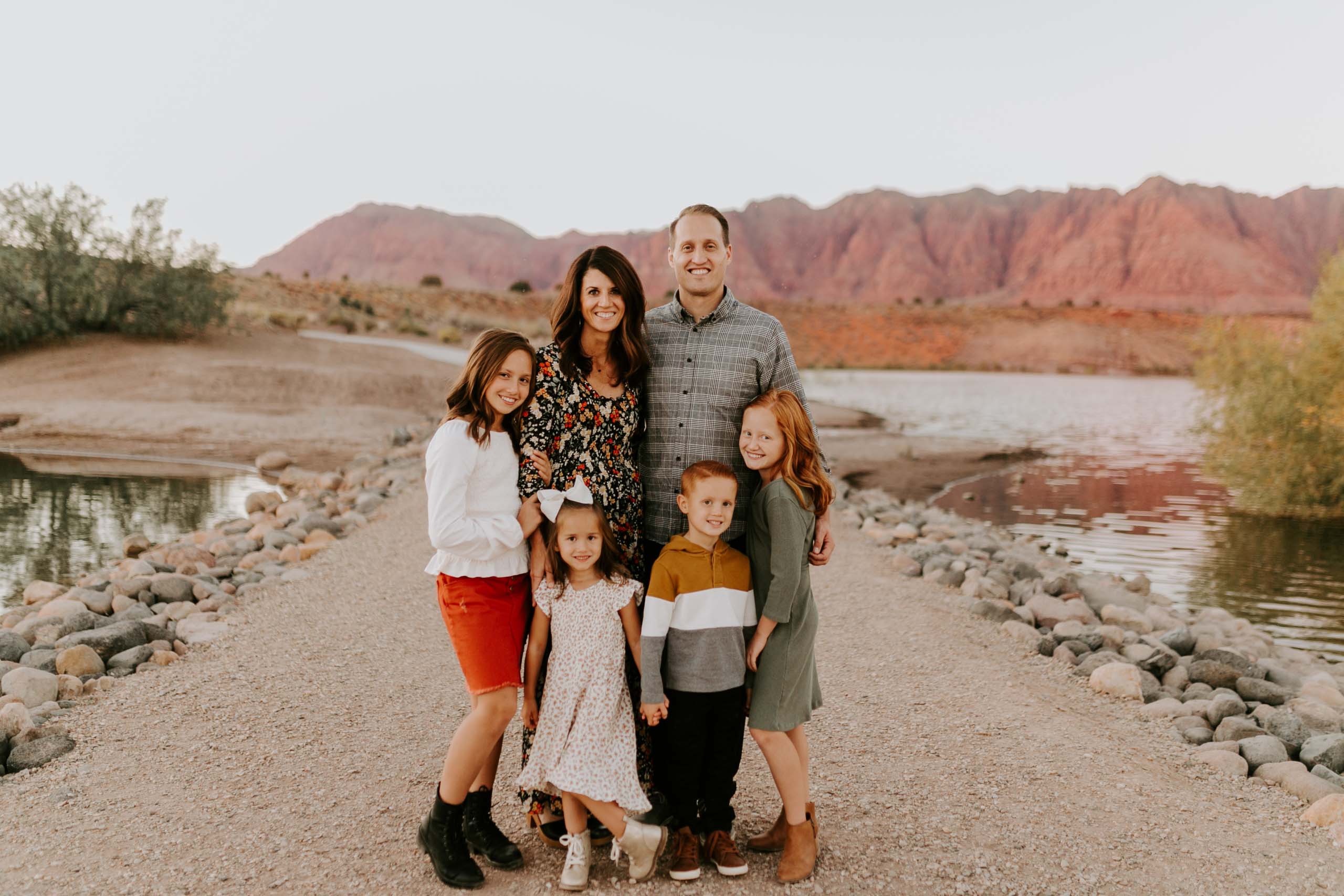 Beckstrom Family photo on gravel path surrounded by lake and red rock mountains.